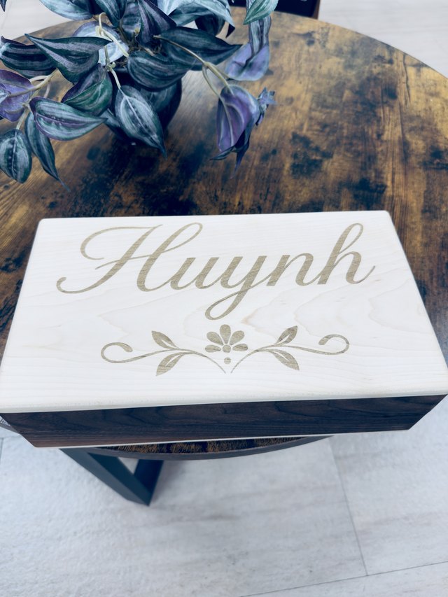Wedding keepsake box with a light wood lid engraved with a family name and floral flourish