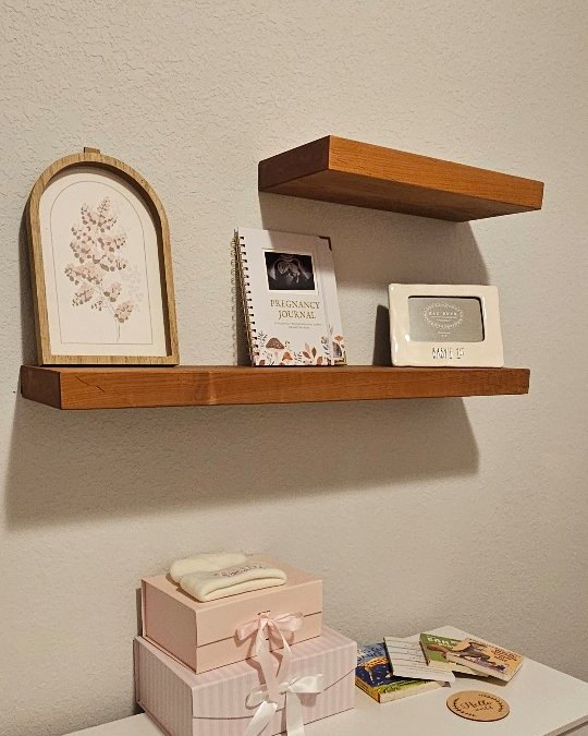 Wooden floating shelves above a white dresser in a nursery